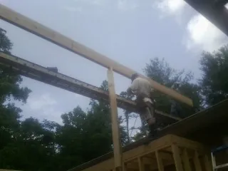 Carpenter setting a ridge beam over a new addition frame — Ice Dam Removal by Roofing Brothers in Winger