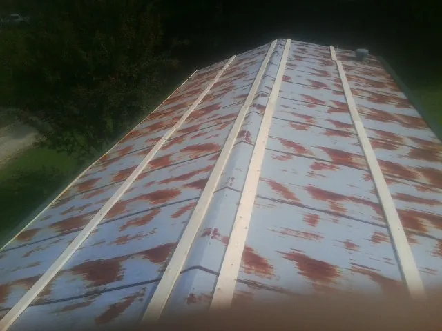 Rusted metal roof panels with new wood purlins before replacement — Storm Damage Roof Repair in Winger by Roofing Brothers