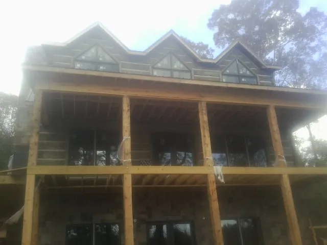 Dormers and porch framing on a large log home under construction — Roof Coating work by our crew in Winger