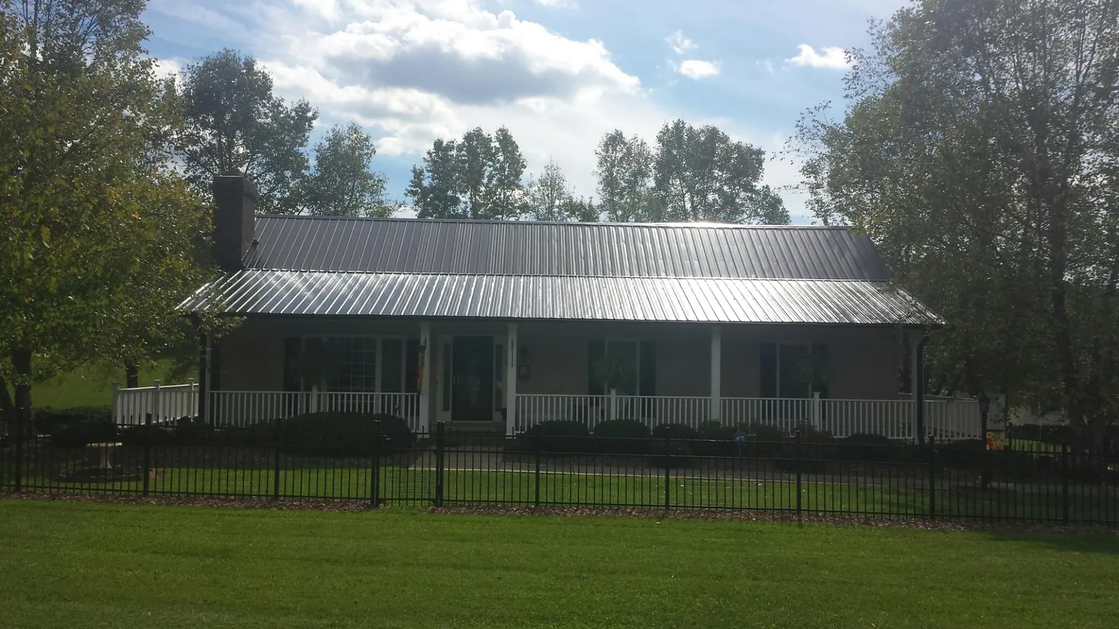 Gray metal roof on a brick ranch with a full width front porch — Gutter Guard Installation work by our crew in Winger