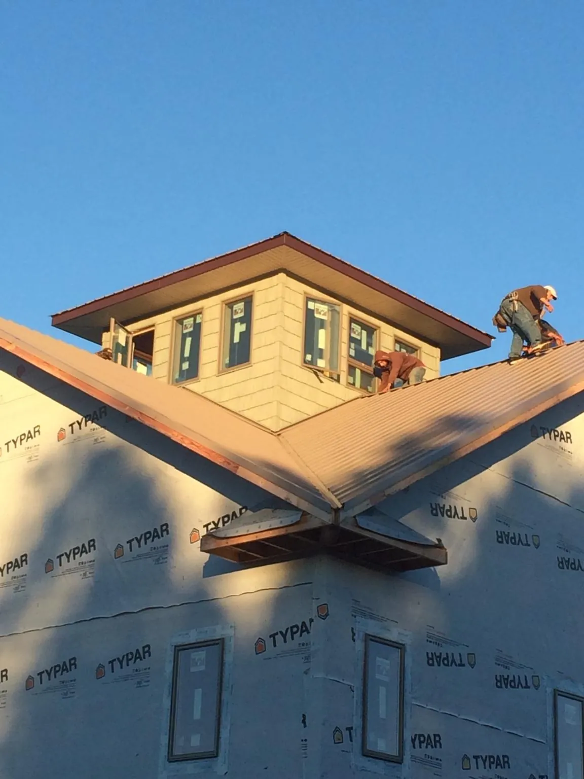 Roofers working around a rooftop cupola on a new metal roof at sunset — Roof Waterproofing in Winger by Roofing Brothers
